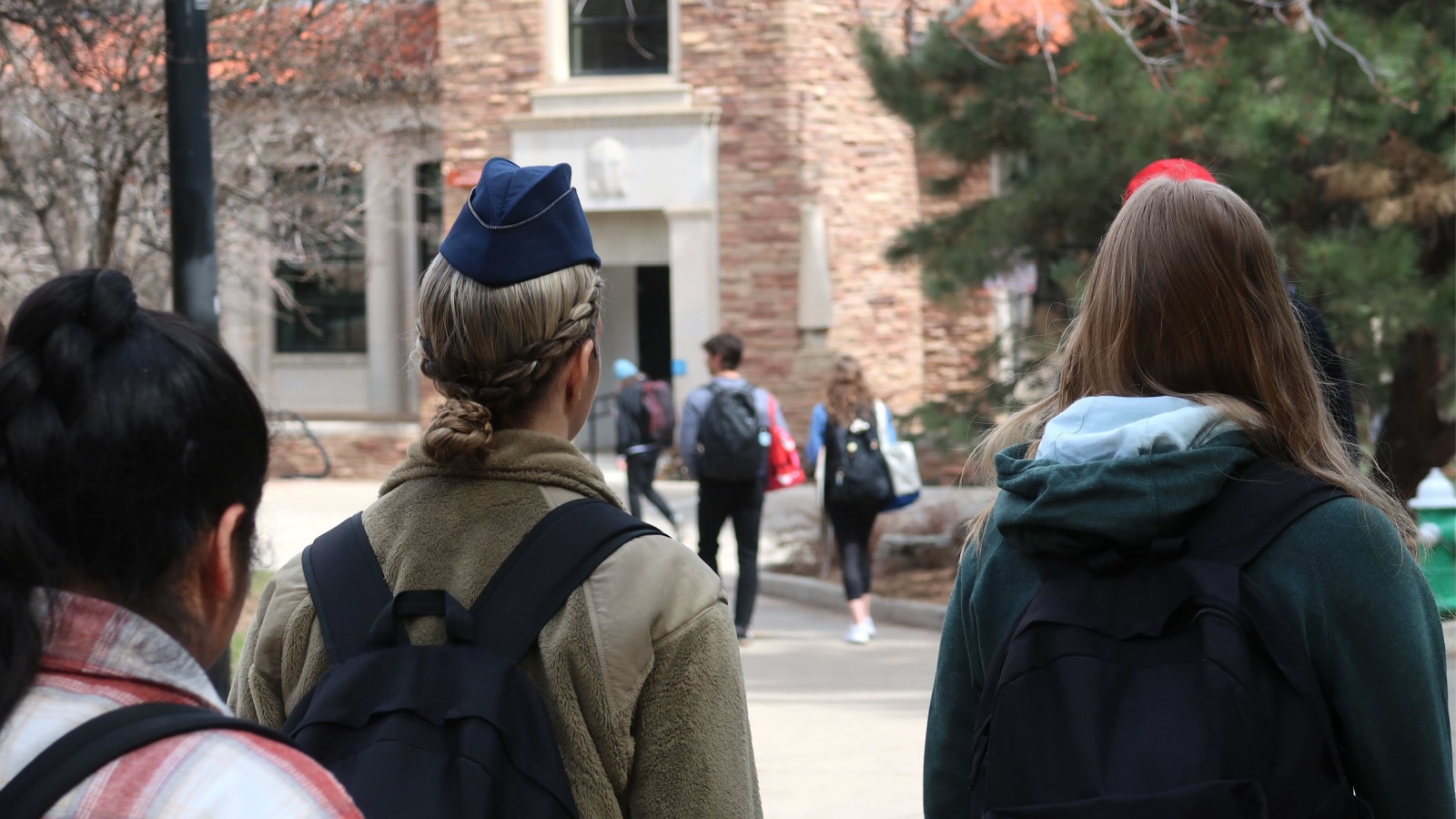A college student on campus wearing an airforce hat to represent the financial benefits of military service.