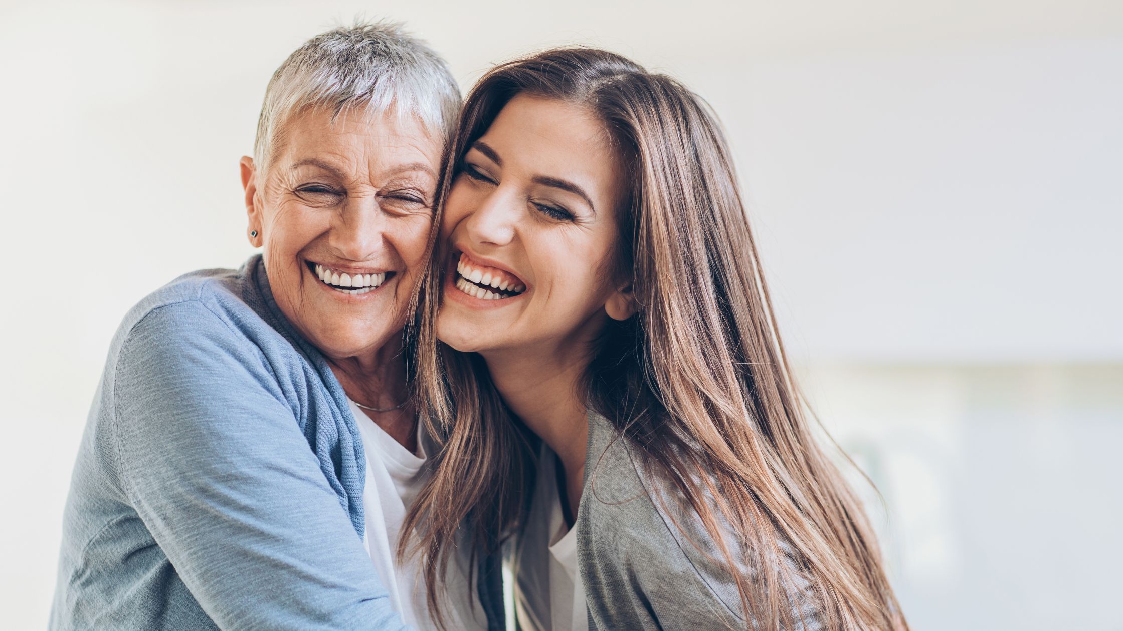 adult daughter hugging and laughing with her mother