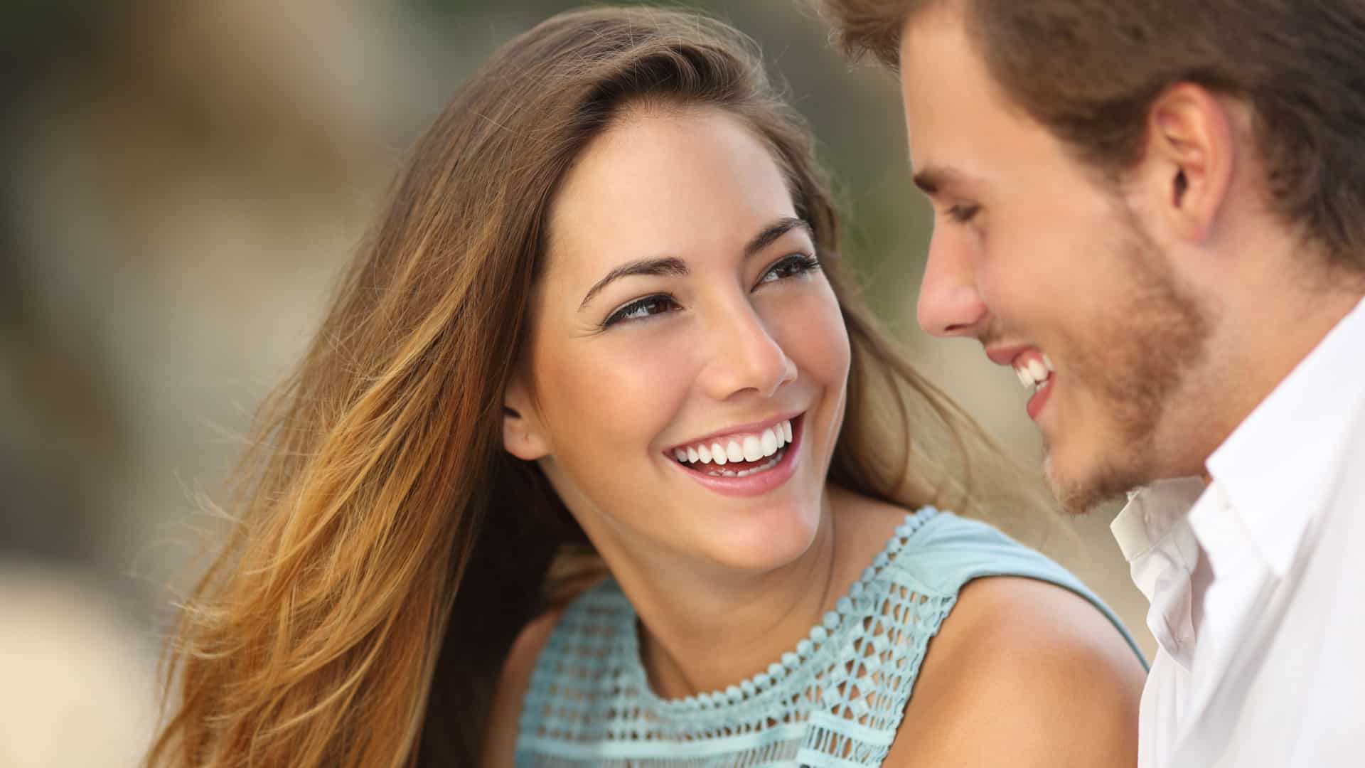 happy woman smiling and talking to her partner to represent an adult conversation to represent things to discuss before moving in together.