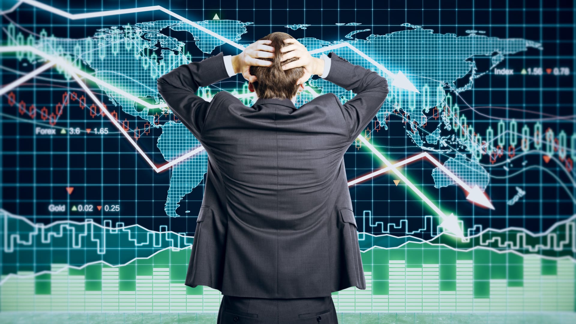 Man looking at financial crash charts with his hands behind his head in a gesture of panic to represent what to do when the market crashes.