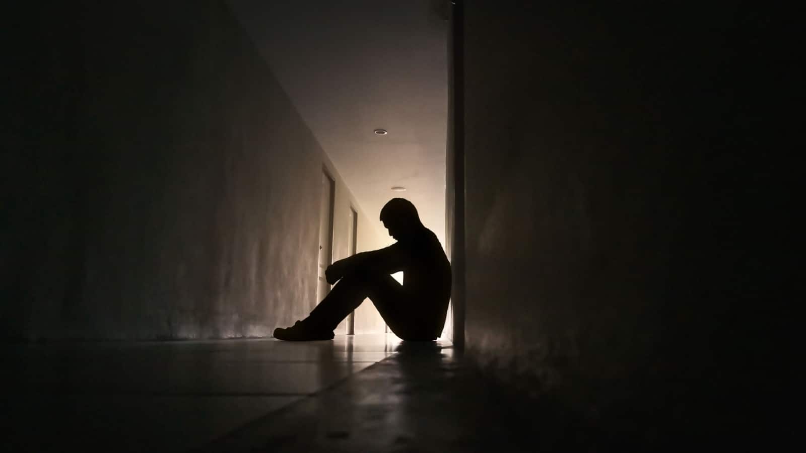Siloutte of a sad, depressed person sitting in a dark hallway to represent someone who has lost everything and what to do when you have nothing.