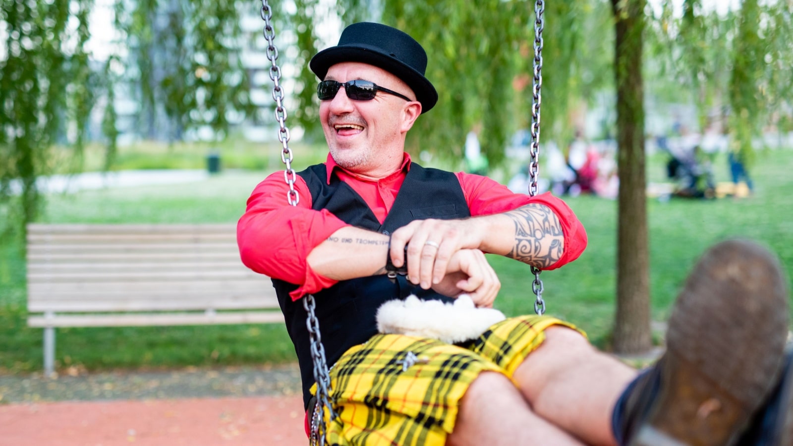 Fun quirky middle aged man having fun at a park by swinging on the swings. Be yourself the way he is.