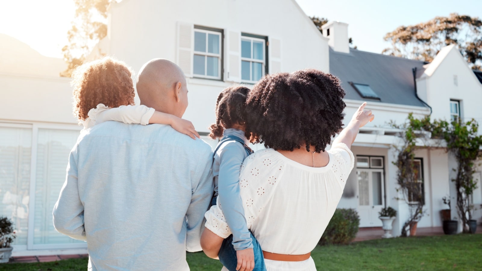 A rear view of a family standing outside their home to represent why you need a home warranty.