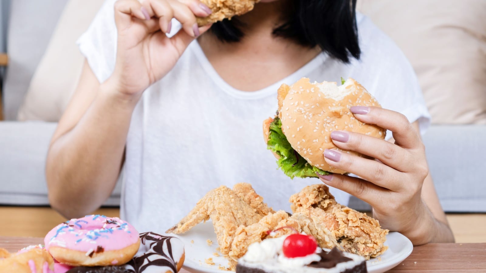 A woman eating a bunch of unhealthy fast food to represent how to stop spending money on fast food.