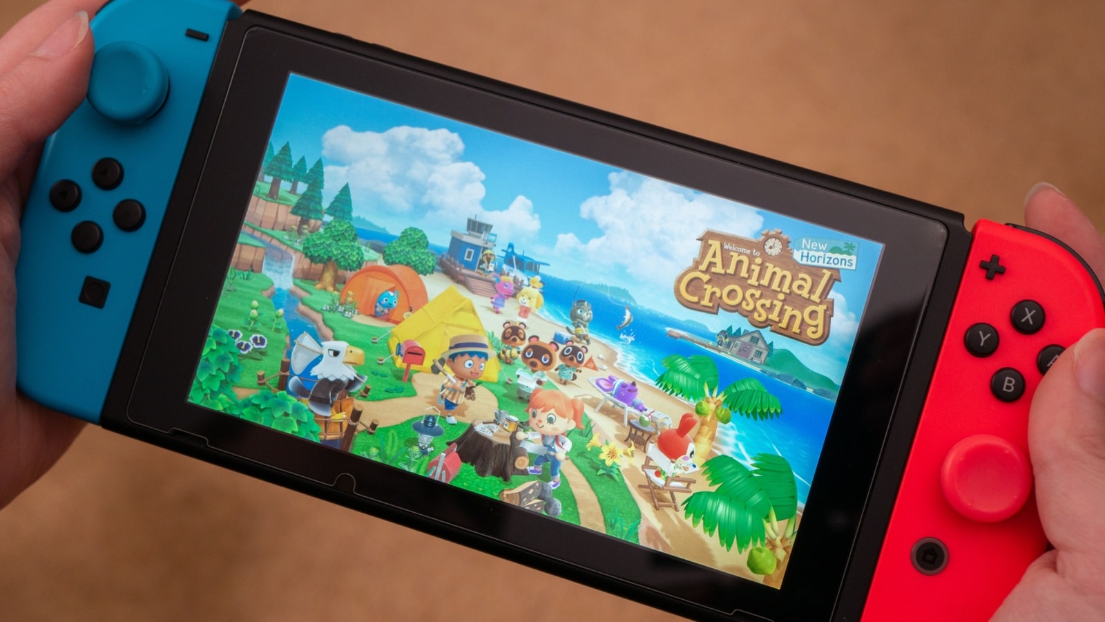 Hands holding a Nintendo Switch with the Animal Crossing New Horizons load screen to represent the question why is Animal Crossing so addictive.