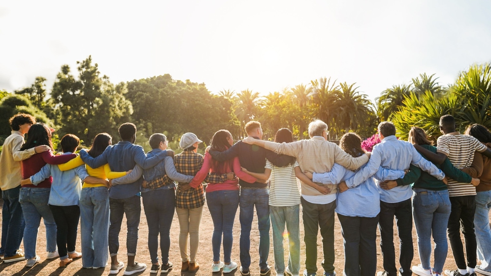 Diverse group of people standing in a line with their arms around each other in a clearing to represent the value of life and ask how much is a human life worth?