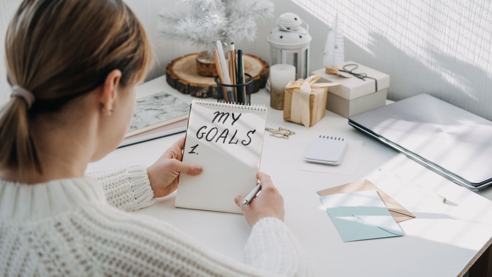 A woman at her desk using goal setting techniques to fill her goal list. She's setting goals for the future.