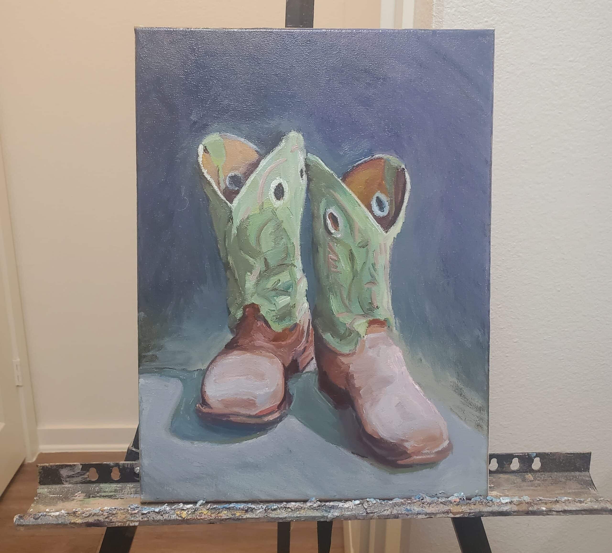 Still-life painting of a pair of boots to represent still-life painting techniques. The painting is on an easel. 