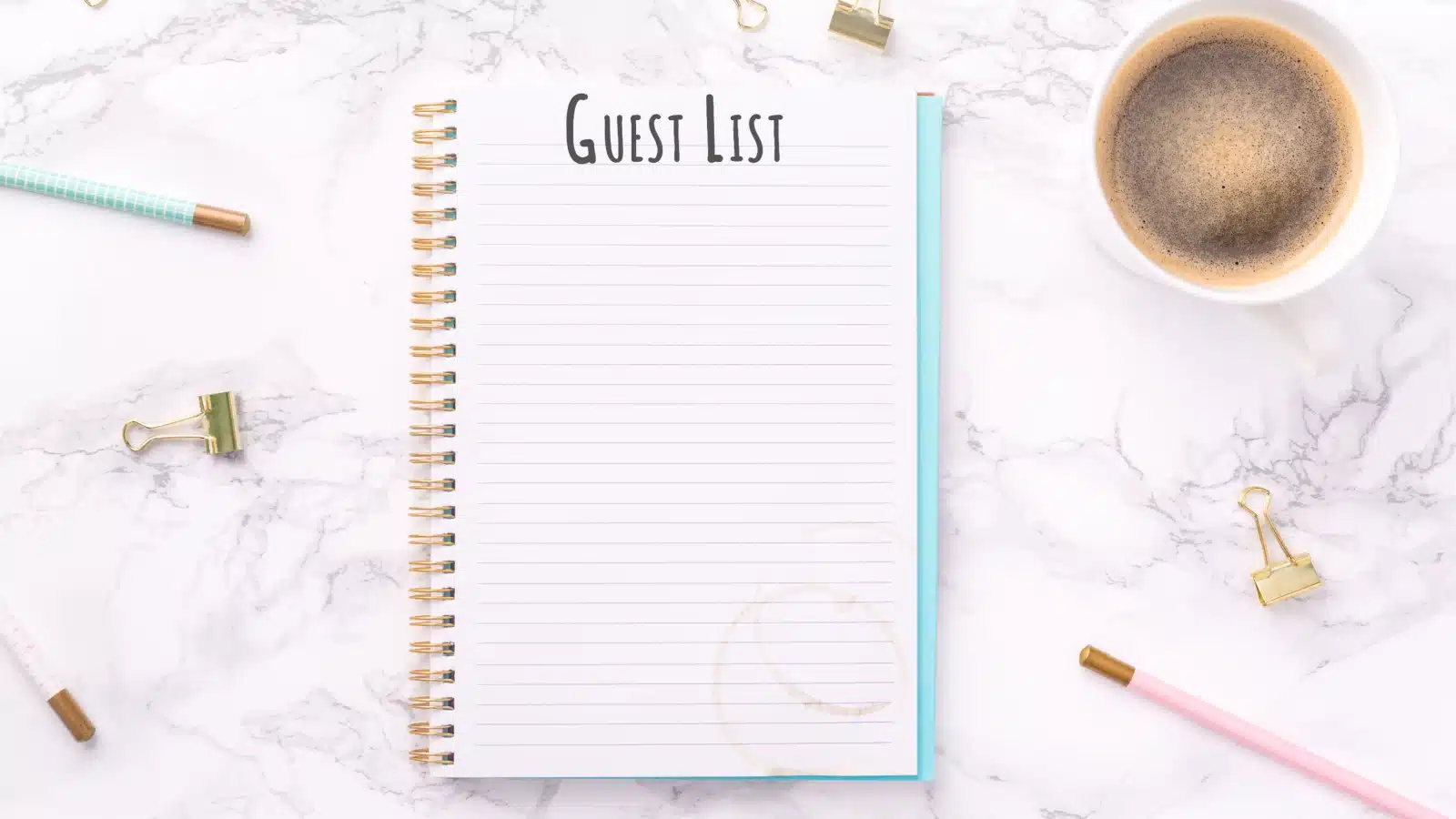 A blank guest list on a counter surrounded by pencils and a coffee cup. 