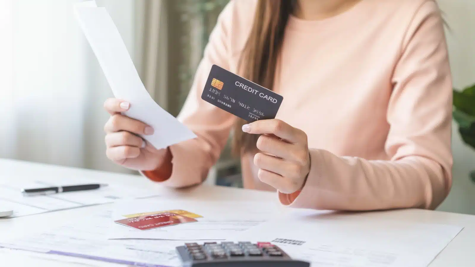 A woman reviewing her spending with a credit card in hand. 