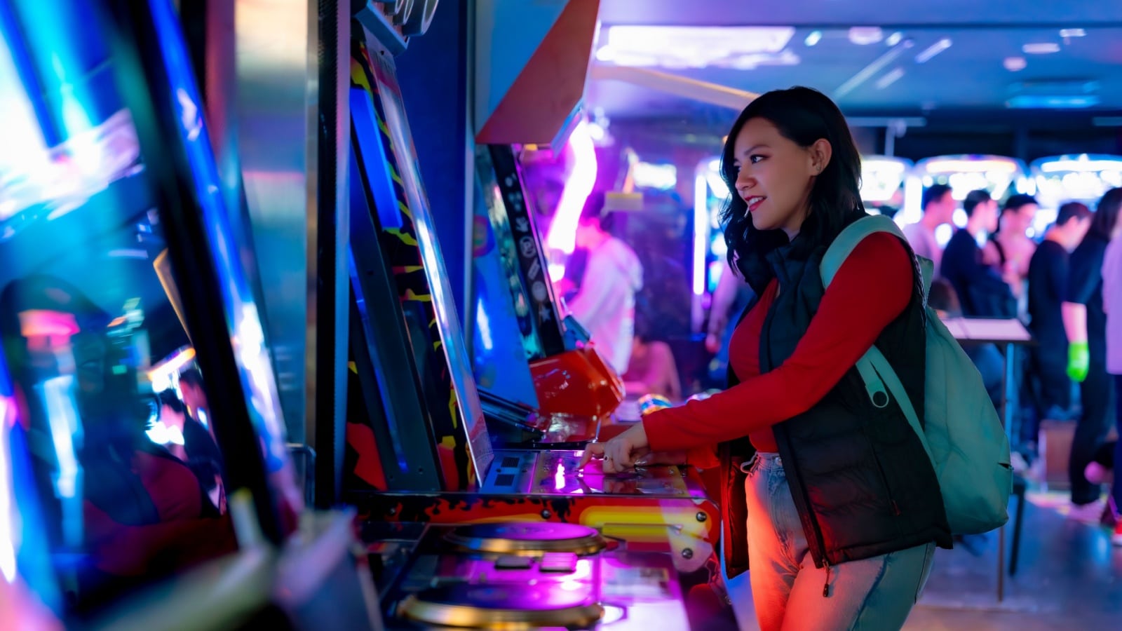 A young woman playing games in an arcade to represent arcade games.