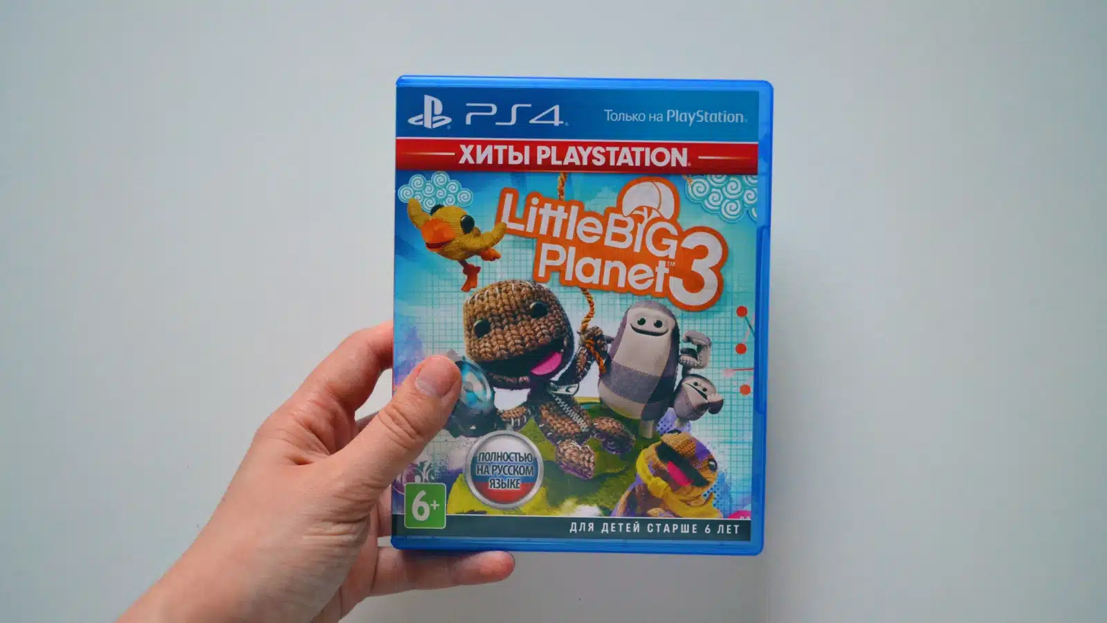 A person holding the LittleBigPlanet 3 game case for PS4.