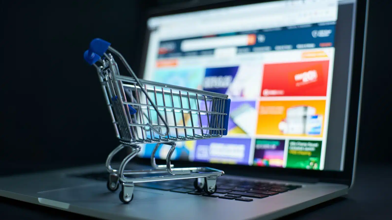 A toy shopping cart rests on a computer keyboard to represent online shopping. 