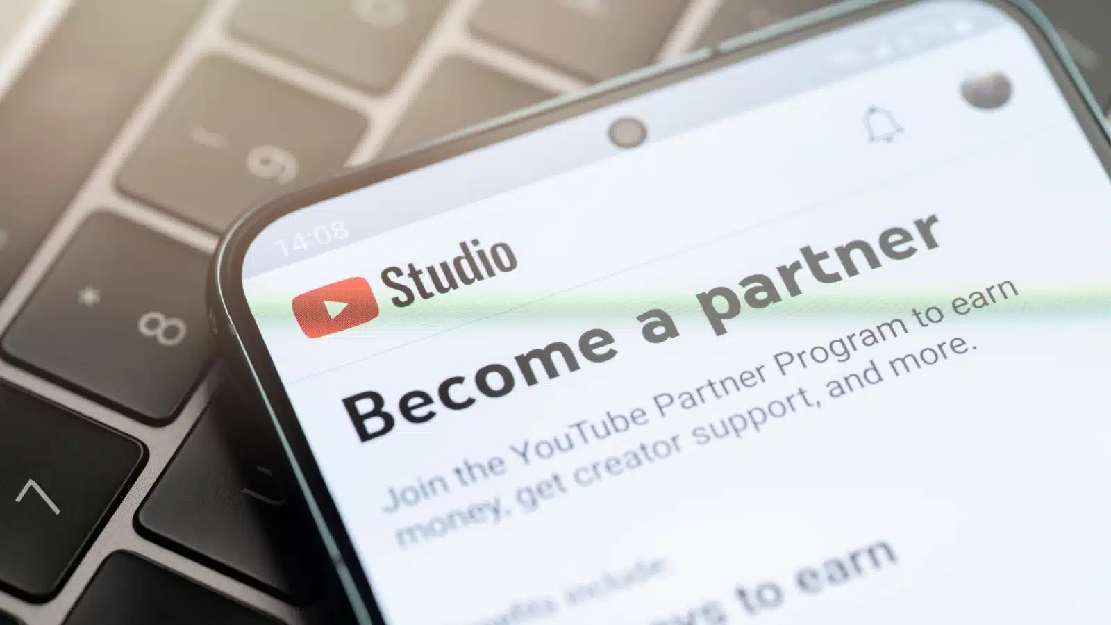Make money on YouTube with the partner program. A cell phone shows the partner program sign up screen. 
