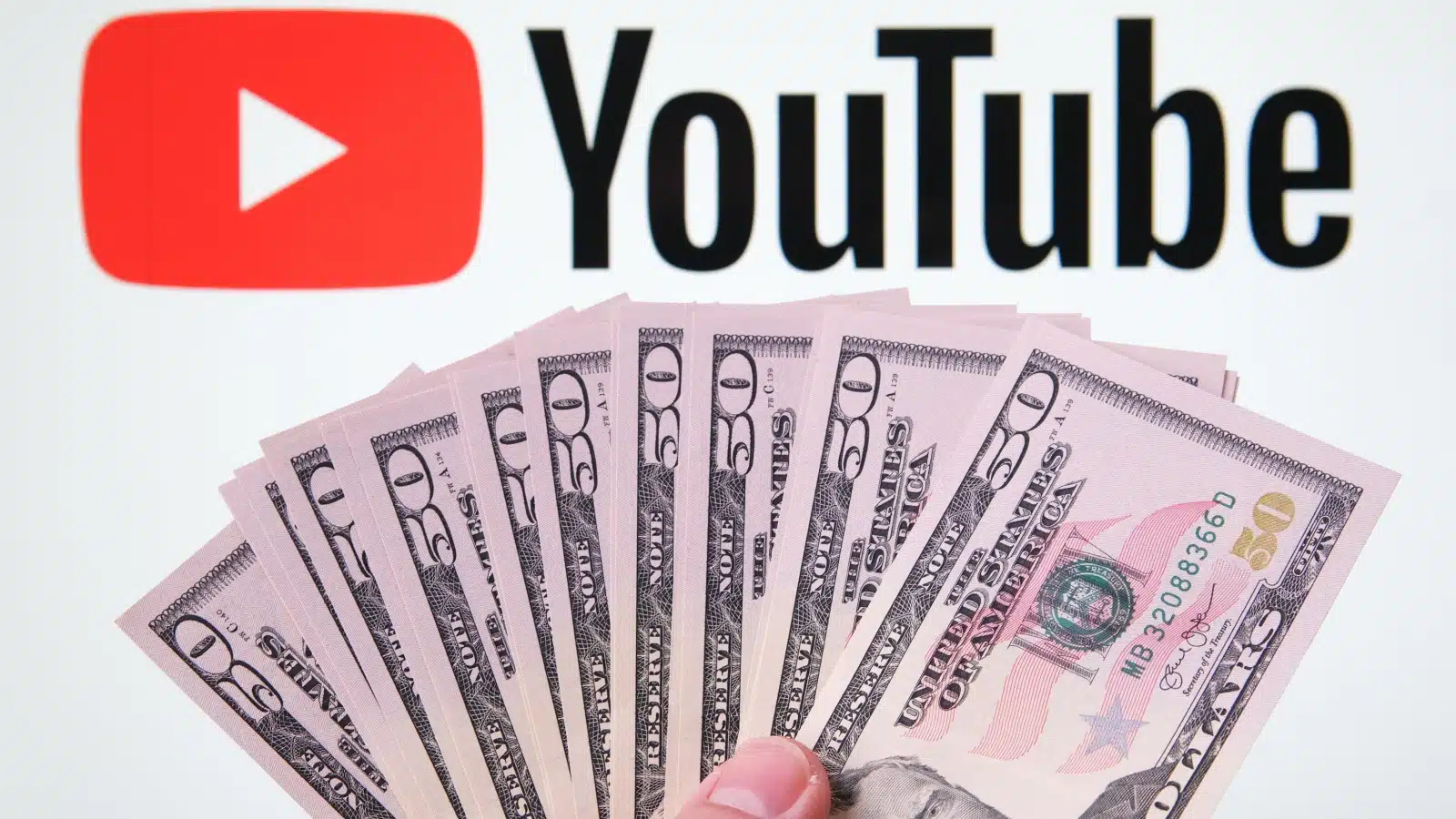 A person holding a fan of $50 bills below a YouTube sign to represent how to make money on YouTube.