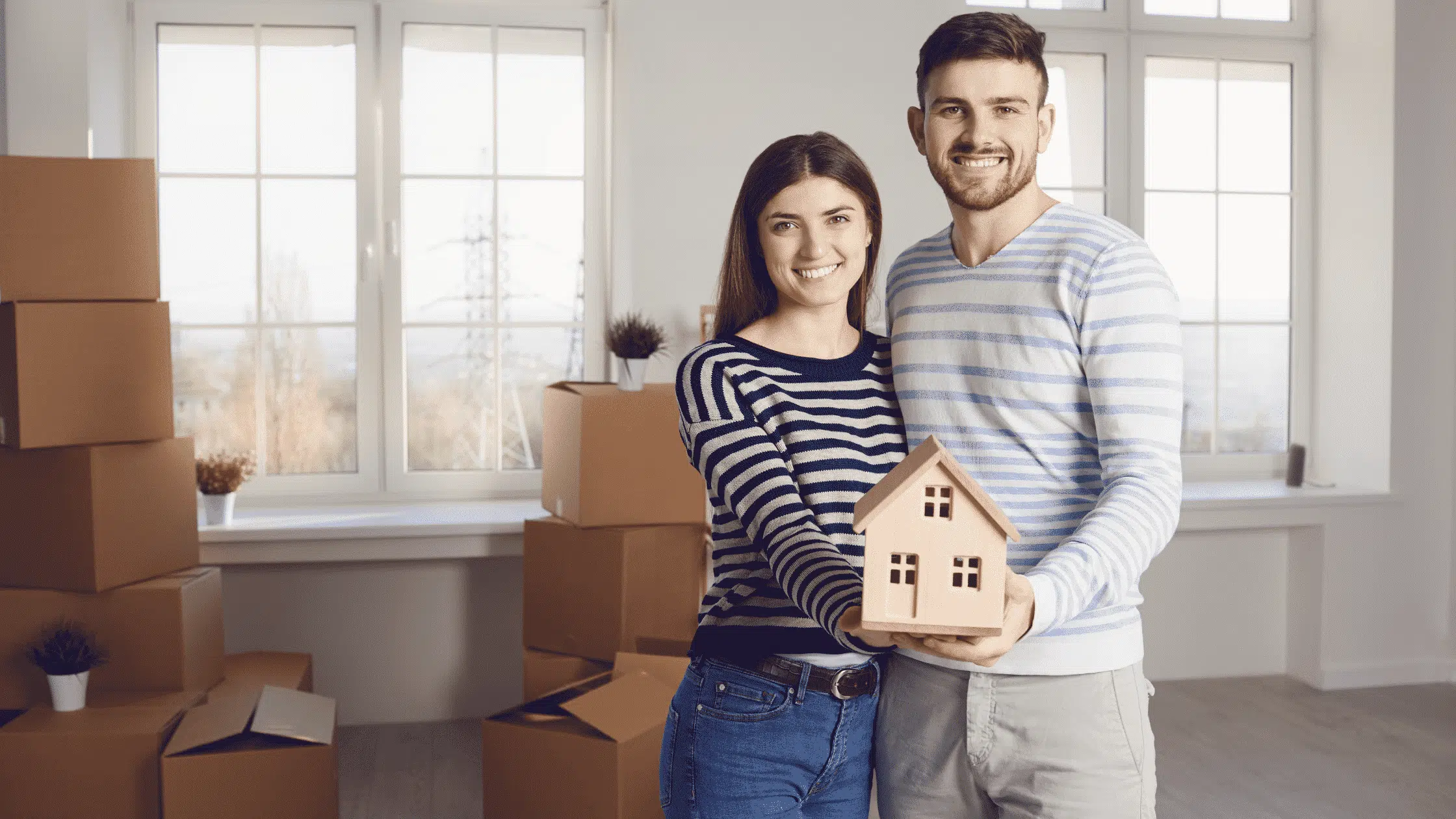 couple holding a model house to represent mortgage rates