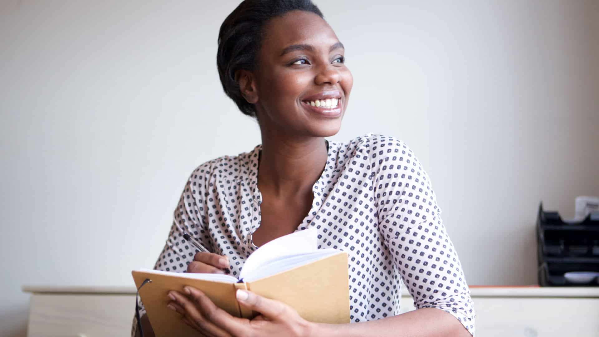 woman smiling and journaling to represent types of journals