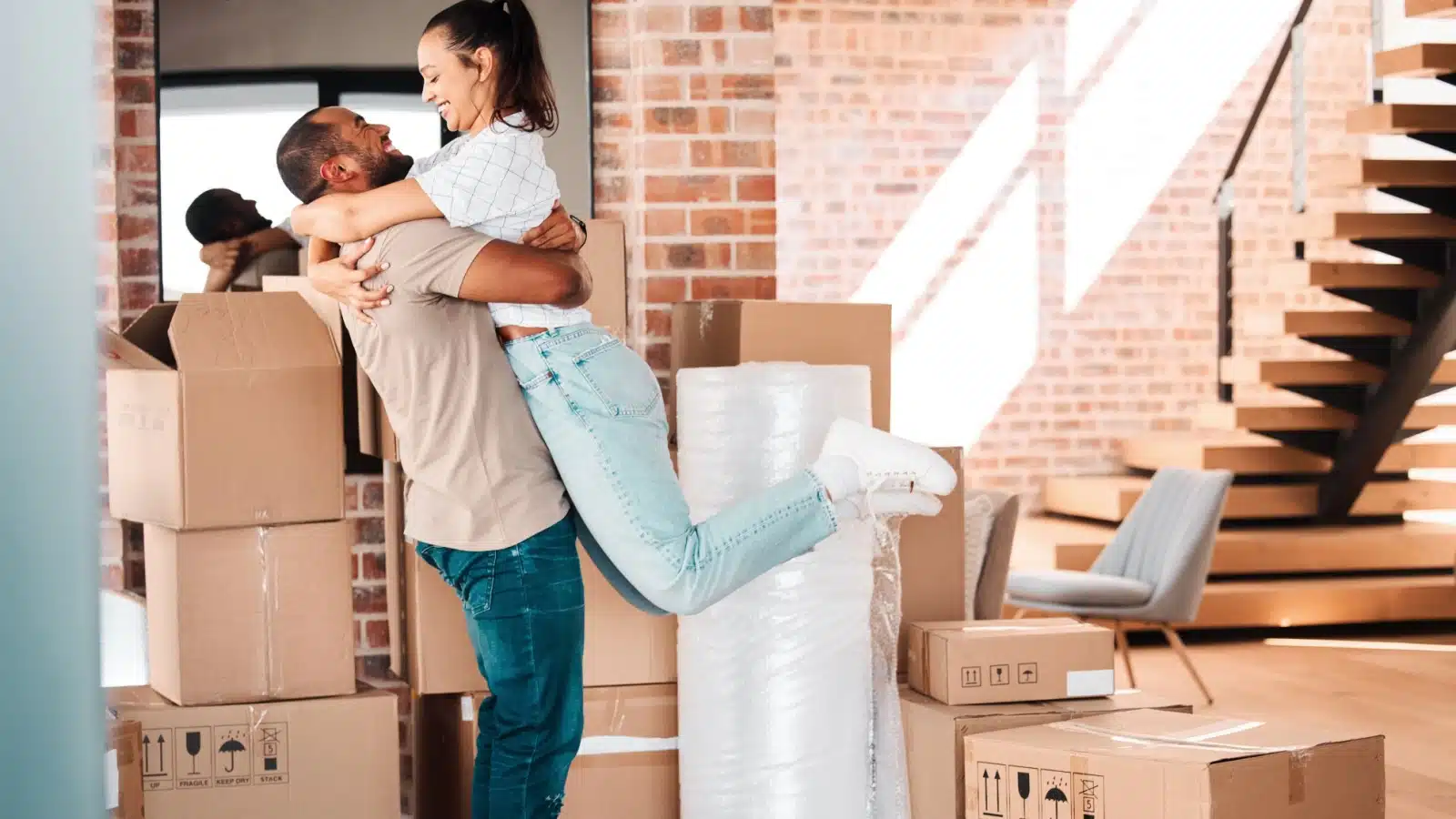 A happy couple hugging in the middle of moving boxes to represent Geoarbitrage.