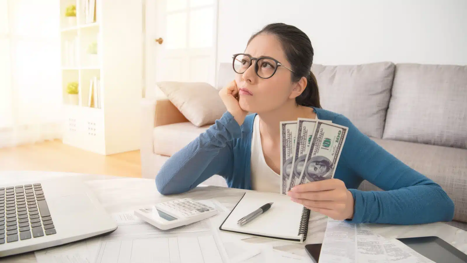 A young women thinking about money to represent the question "how much money do you need?"