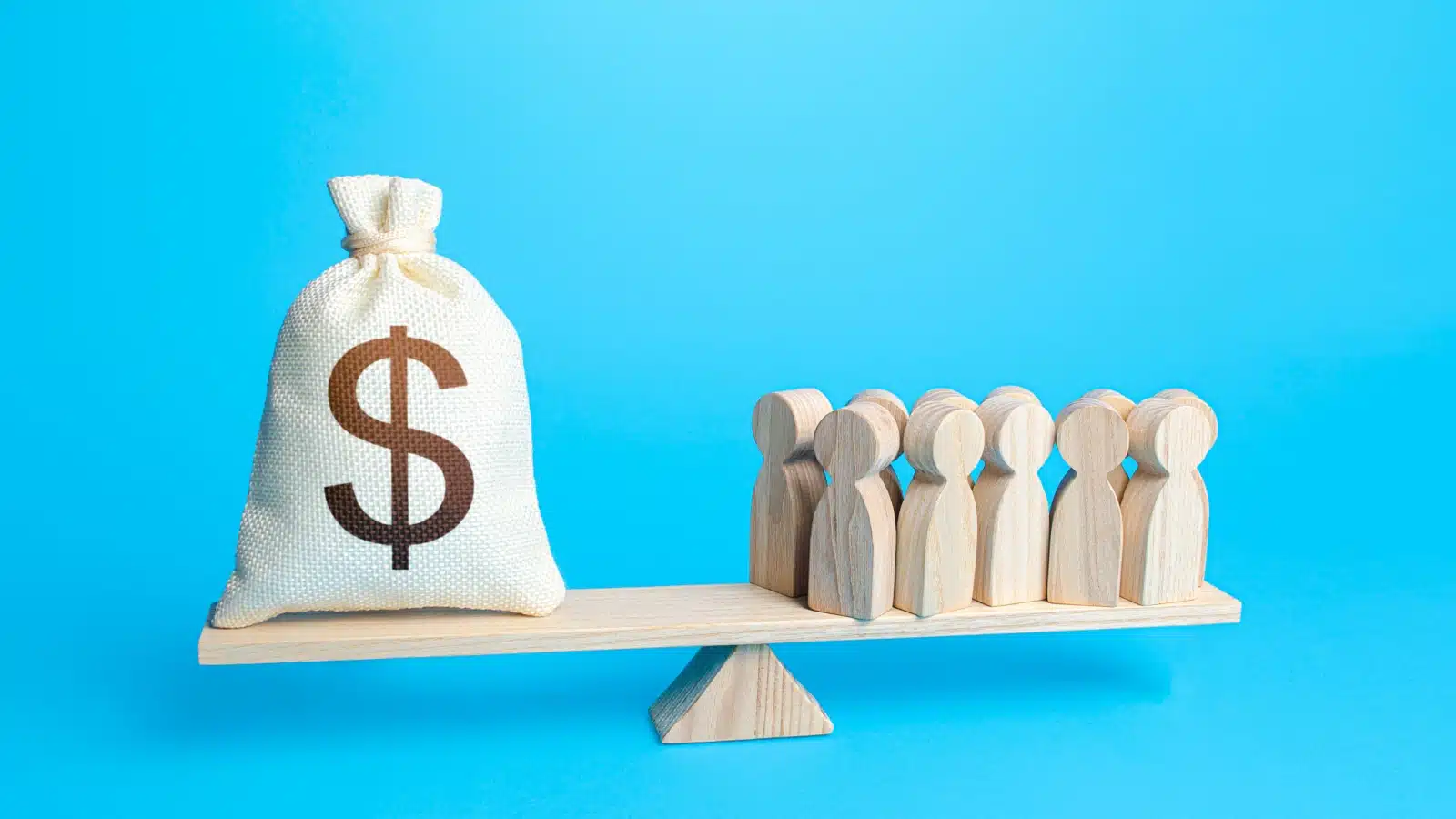 Graphic featuring a scale with a bag of money on one side and a group of human shaped wooden figures on the other to represent productivity vs. wages.