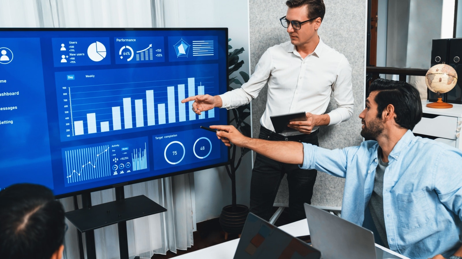 A business meeting with statistics shown on a monitor. 