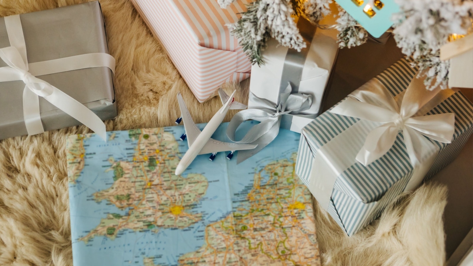A gift wrapped with map paper with a small airplane on it surrounded by other presents to represent gifts for travelers.