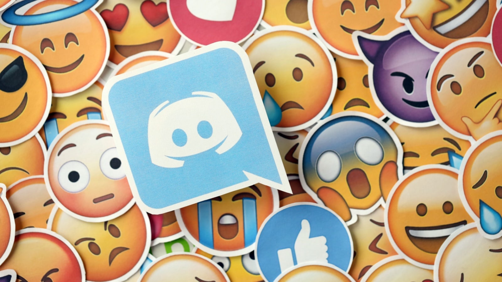 A graphic showing the Discord logo on top of a pile of standard emoticon to represent Discord emotes.