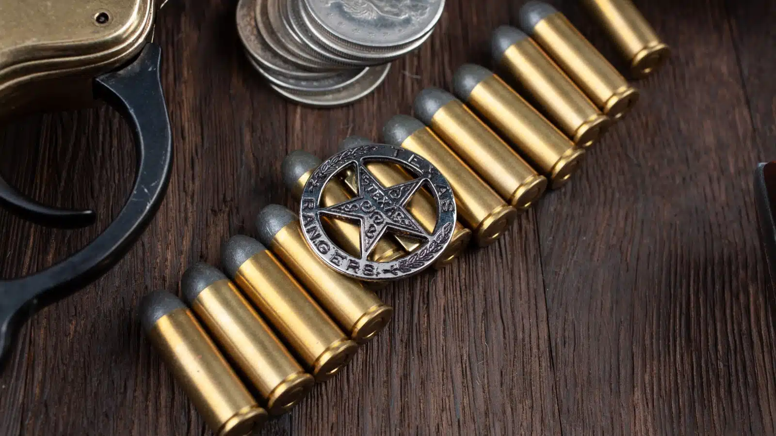 A historic Texas Ranger badge rests atop a line of bullets with a few other historical items around the edge. 