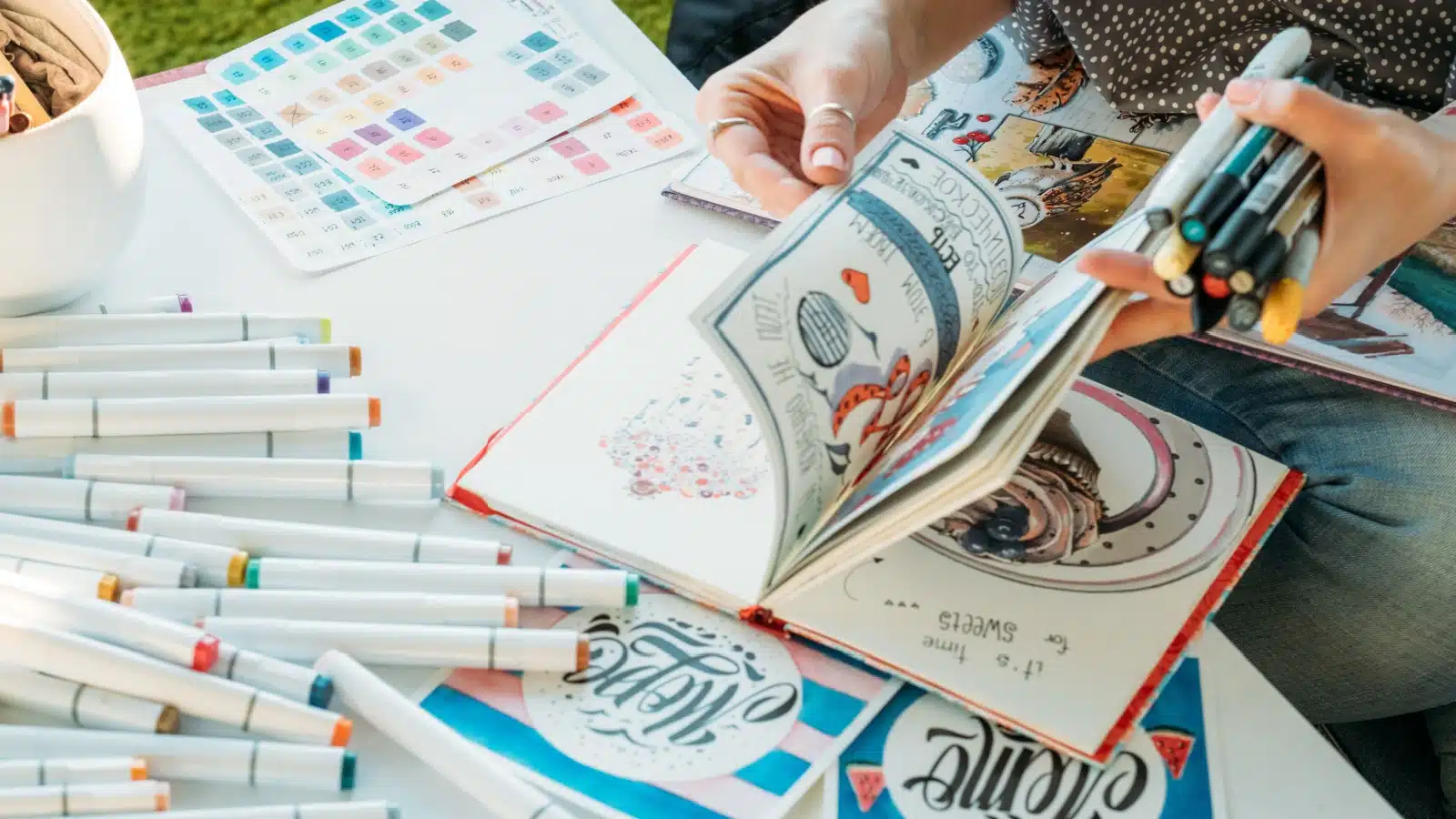 A person leafing through the pages of their colorful art journal.