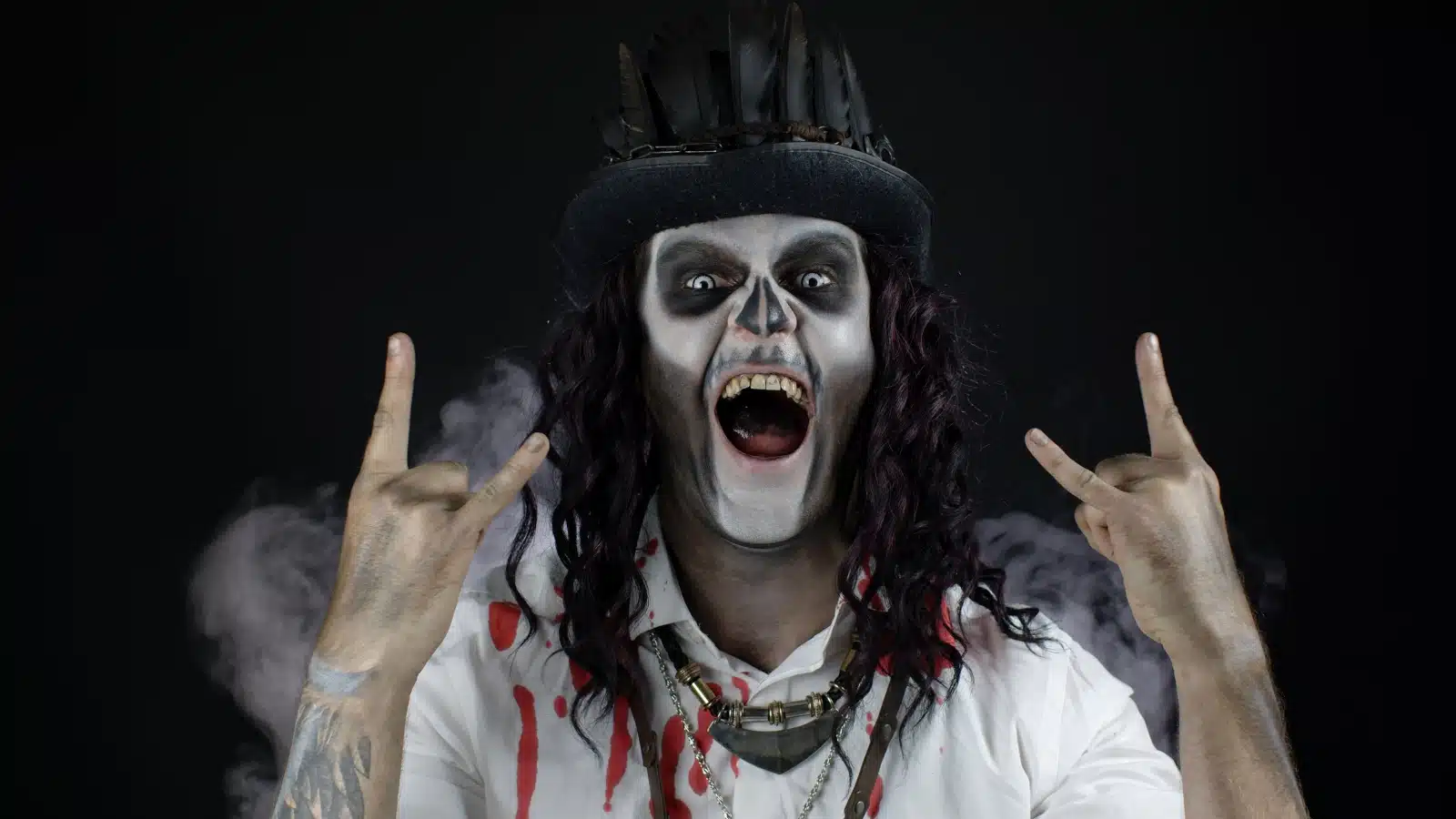 A man in a monster costume making the rock sign with his hands to represent monster music and songs about monsters.