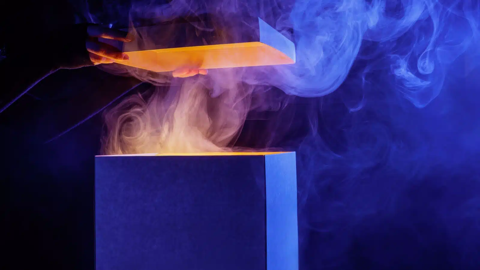 Hands opening a mystery box with smoke coming out of it to represent a subscription horror box.