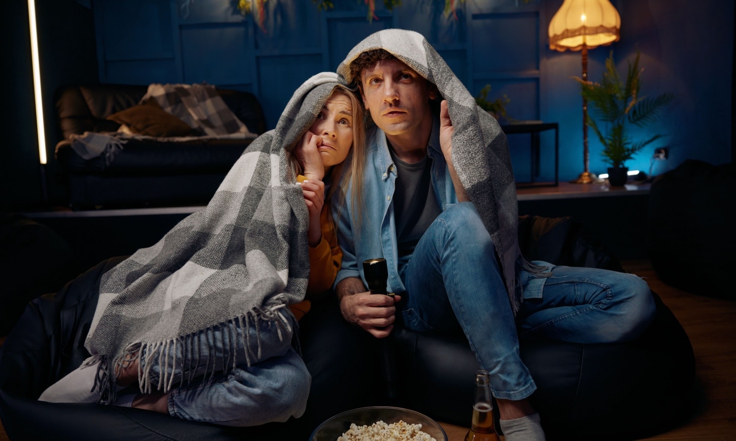 A couple snuggled on the couch watching a scary movie to represent the best Halloween movies.