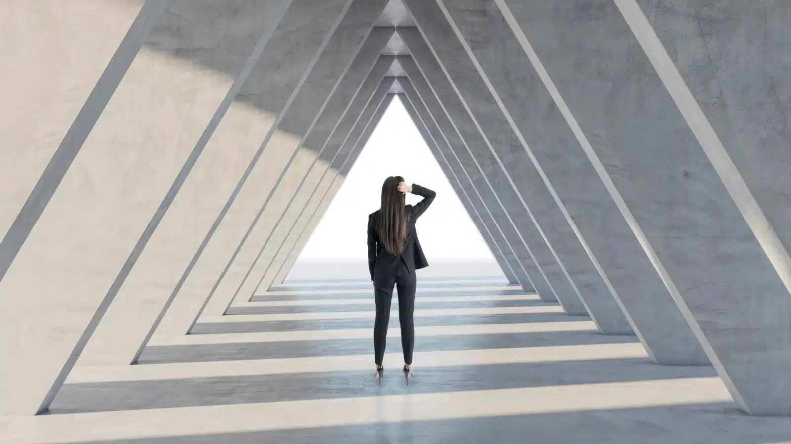 An unsure woman standing in a hallway shaped like a triangle. 