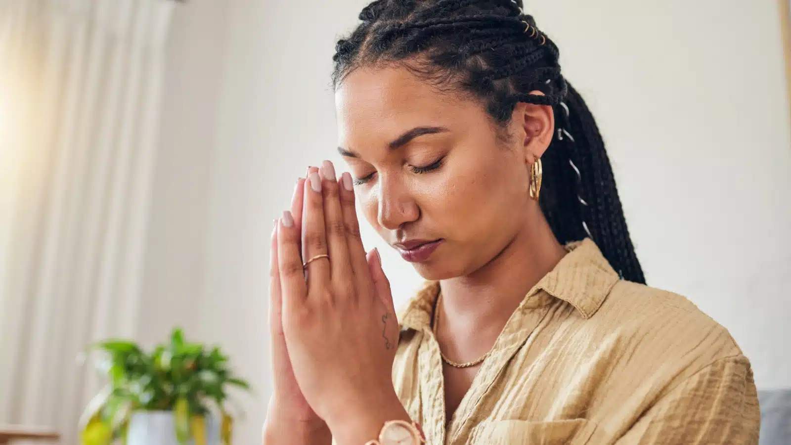 A woman with her head bowed and hands clasped in prayer.