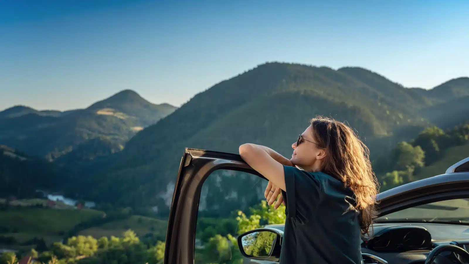 A carefree woman enjoy the view from her car on a road trip.