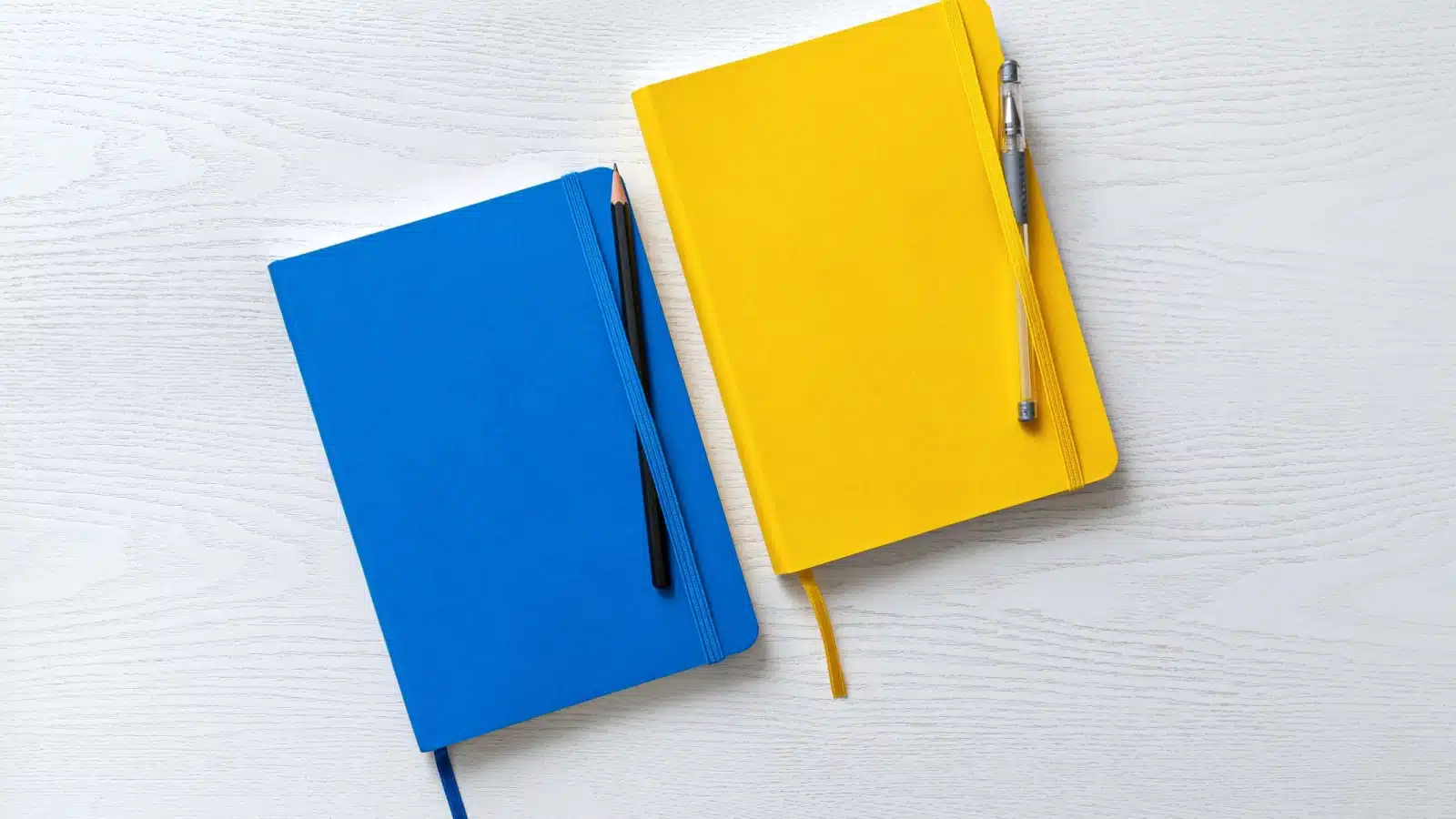 Two hard covered journals. One has a pen, the other has a pencil. These represent the only bullet journal supplies you need to get started.