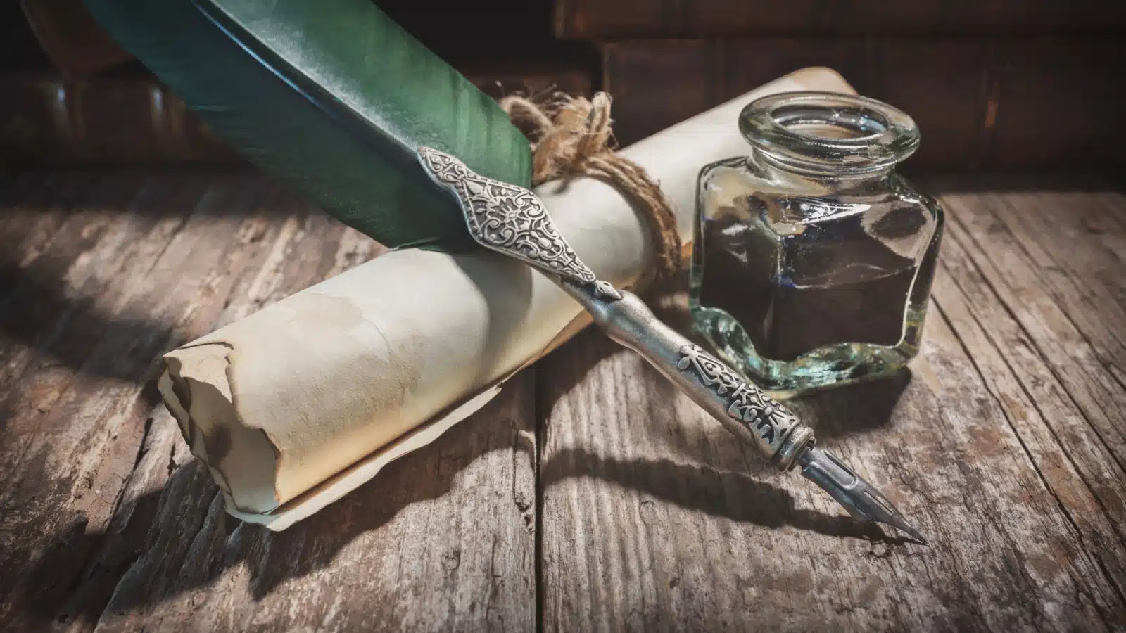A quill pen, ink, and a rustic scroll to represent a calligraphy set.