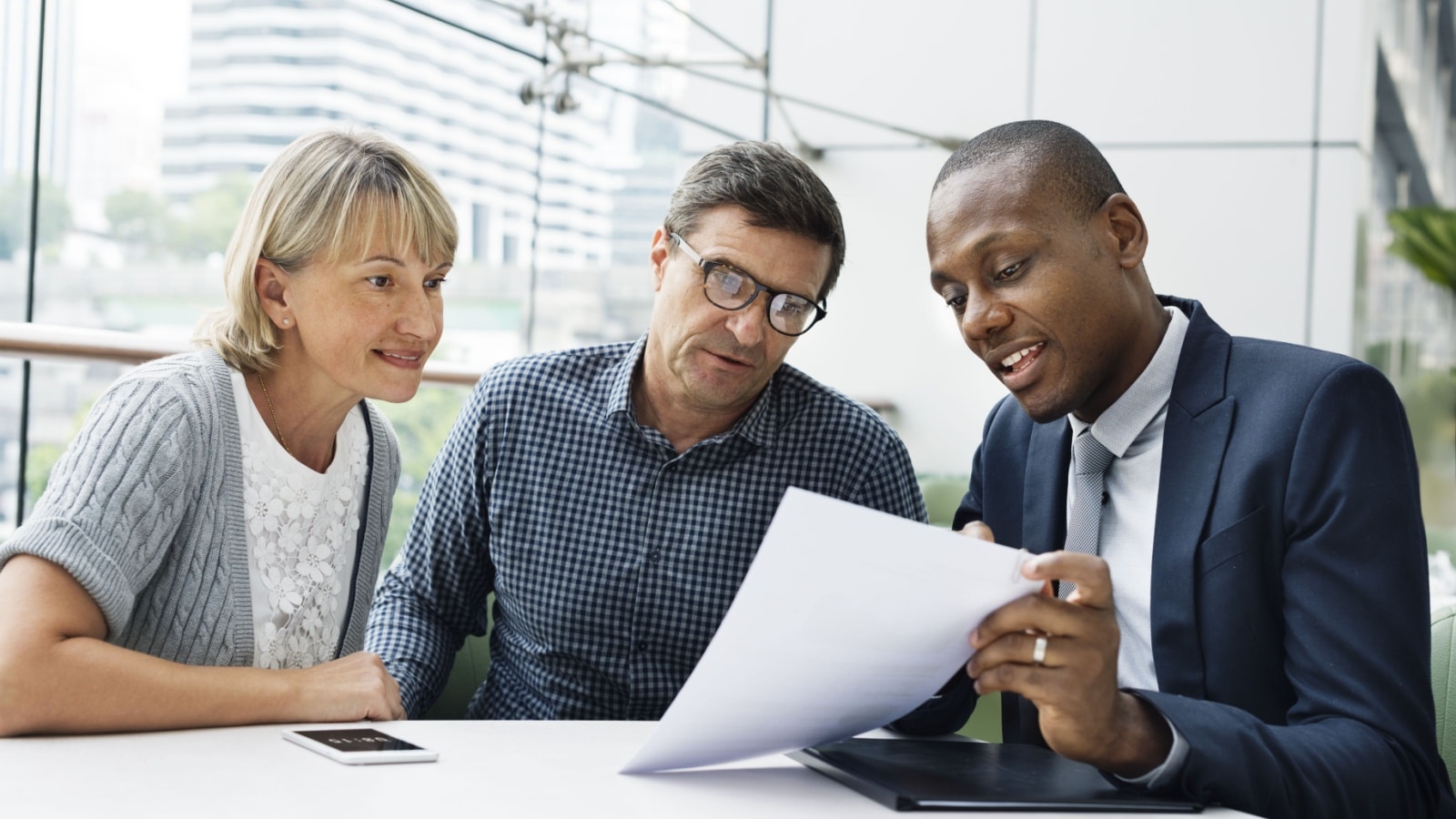 A banker reading the fine print on a new savings account to a couple. They decided to switch banks to take advantage of rising interest rates.