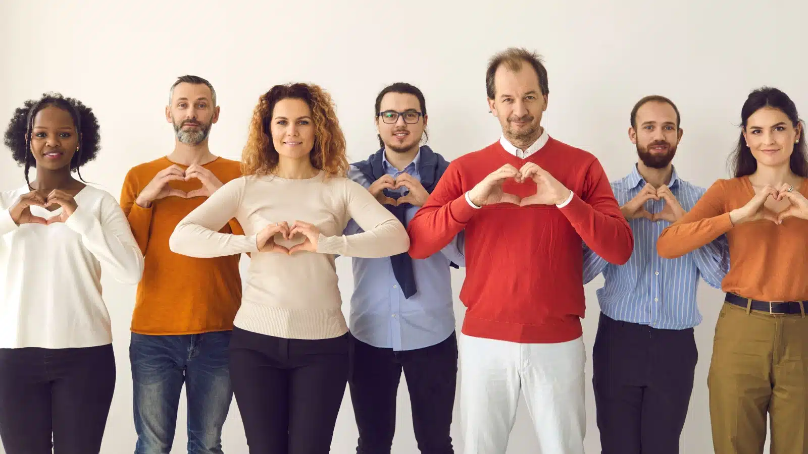 Diverse group of people all making the thankfulness heart with their hands to represent both thankfulness and gratitude.