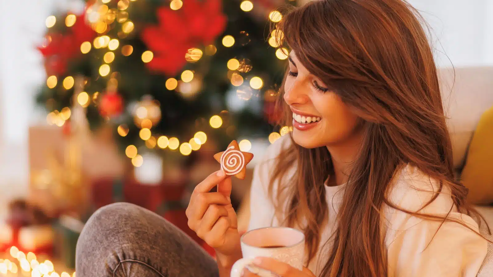 A woman eats a Christmas cookie to represent the best Christmas flavors.