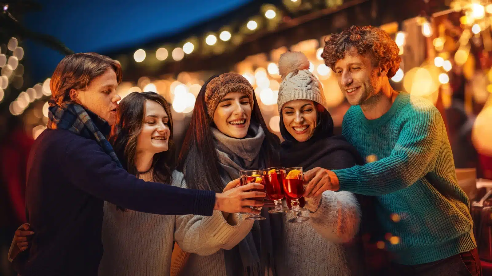 A group of friends giving cheers with glasses of mulled wine for Christmas.