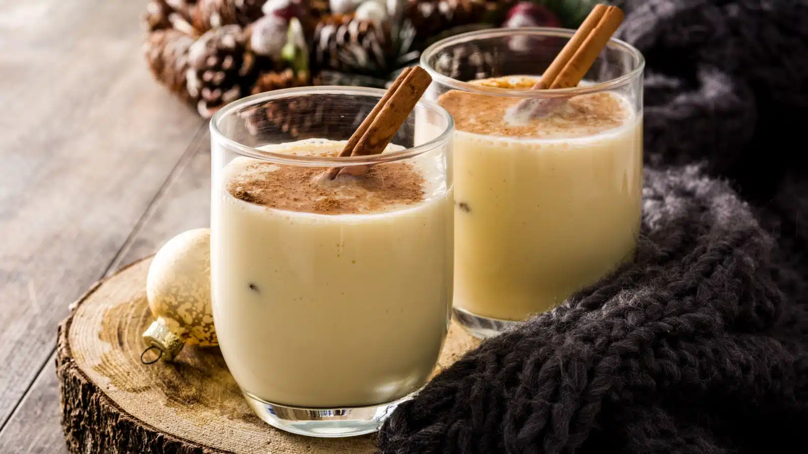 two glasses of eggnog with cinnamon sticks.