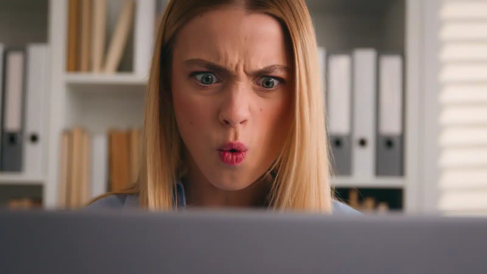 A woman rages at what she's seeing on her laptop to represent righteous indignation.