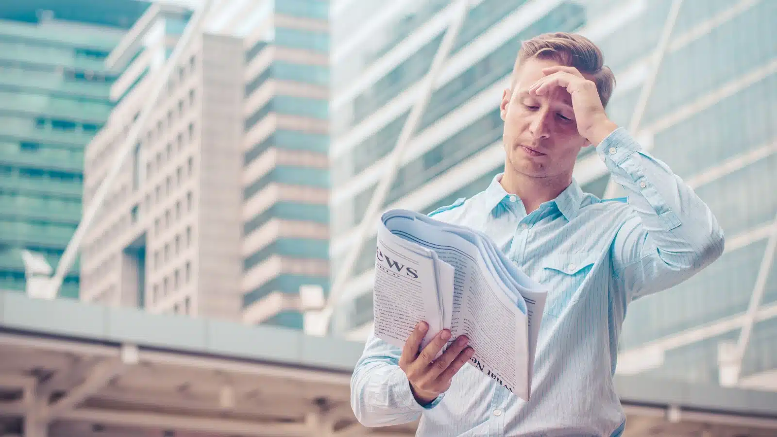 A man is visibly upset while reading a newspaper. 