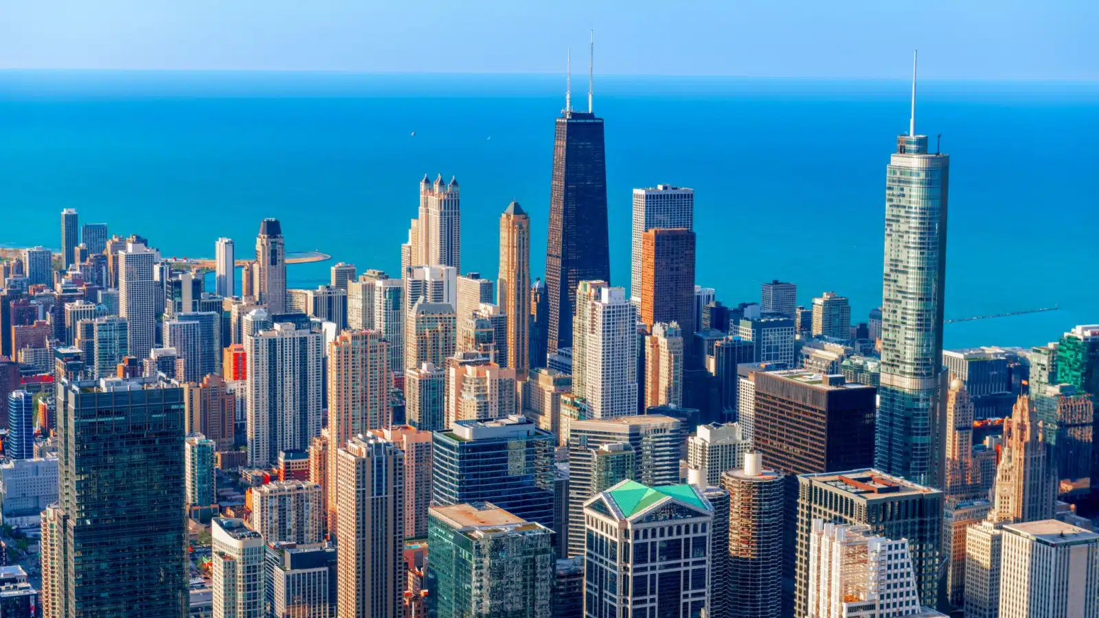 A view of the Chicago skyline featuring the Handcock building and Lake Michigan from high in the air.