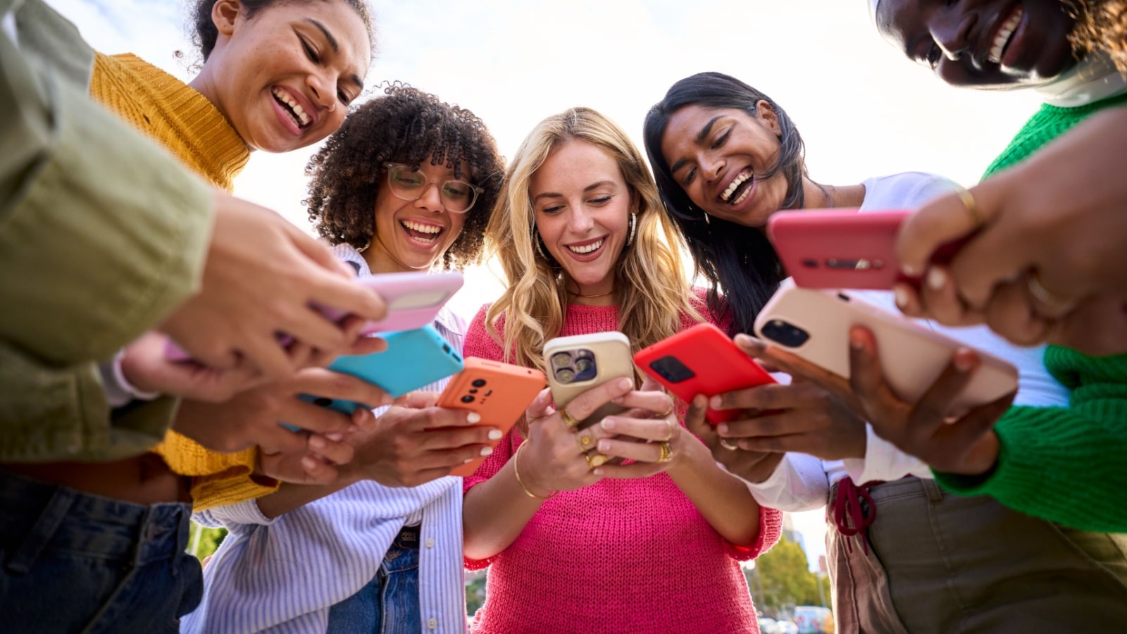 A group of smiling teenagers all on their phones to represent common complaints about Gen Z.