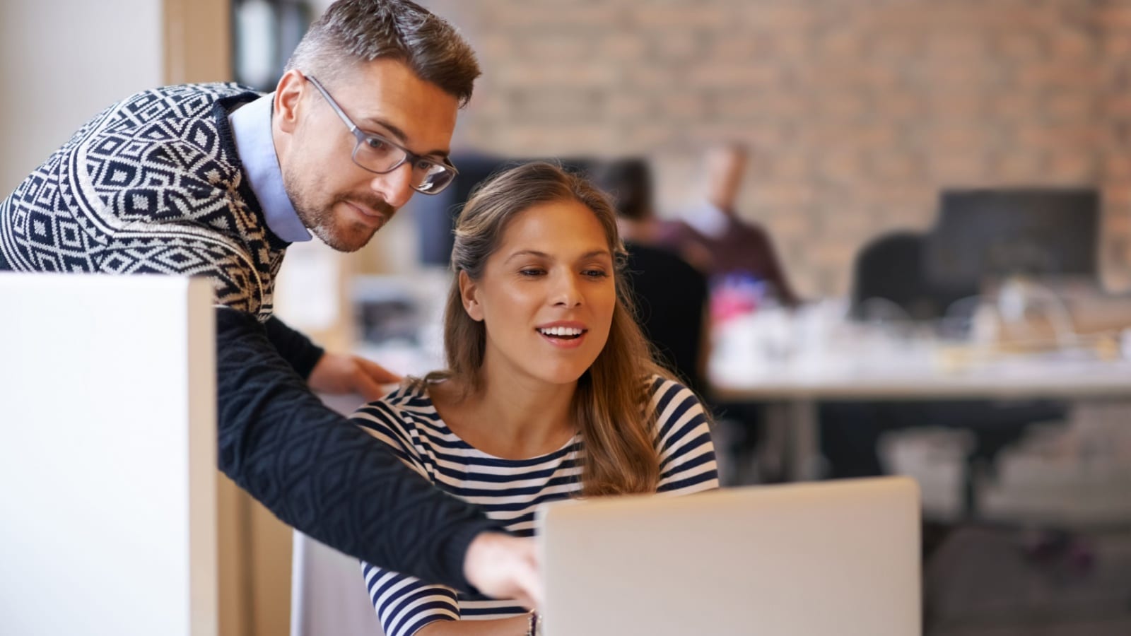 A manager providing constructive criticism to an employee about a project on their laptop.