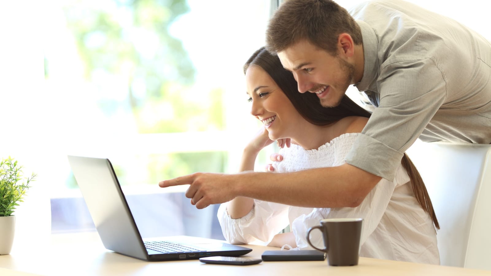 A happy couple is looking at something online with her laptop, to represent the best free things on the internet.