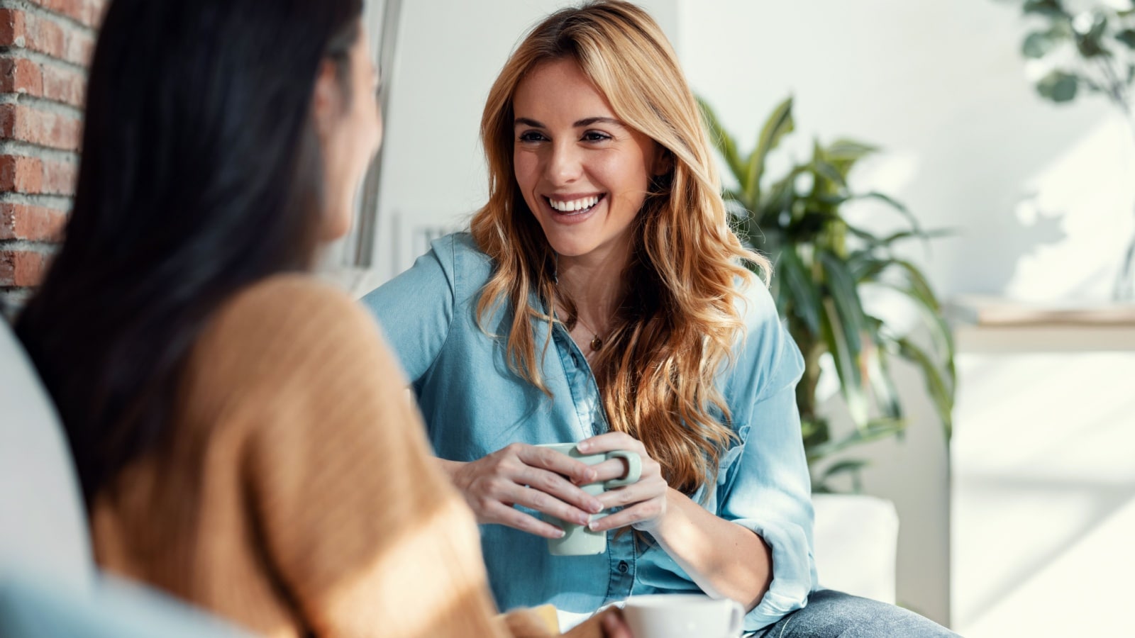 Two happy women talking on the couch to represent the vital life skills you need for a happy life.