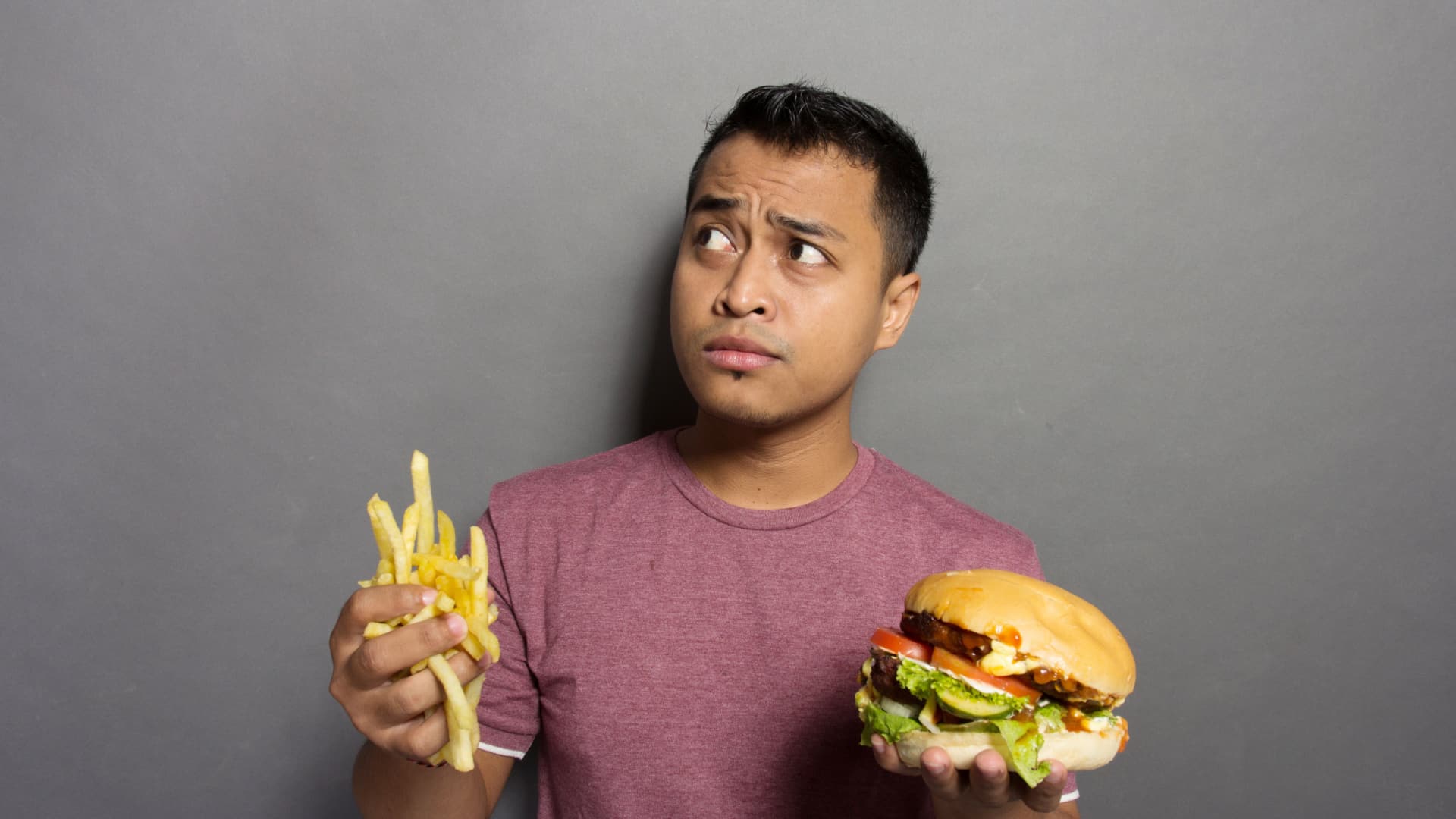 Man looking sideways holding burger and fries.